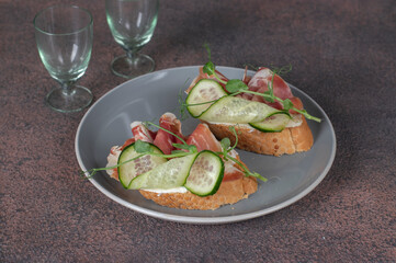 Sandwiches with cream cheese, jamon and cucumber on gray plate