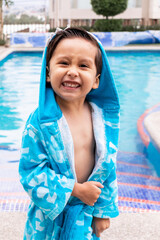 Smiling Boy in Blue Bathrobe Enjoying a Sunny Day at the Pool