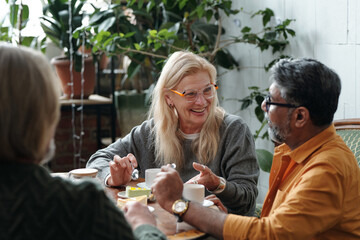 Group of elderly individuals enjoying lively conversation at cozy cafe. Natural light illuminating...