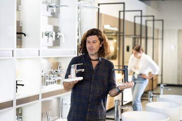 Man inspects and chooses new kitchen or bath tap faucet at a hardware store