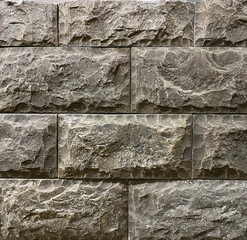 Textured gray stone wall made of large rectangular blocks in a modern architectural setting