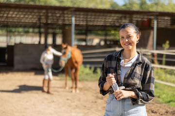 Young woman poses while cleaning horse paddock