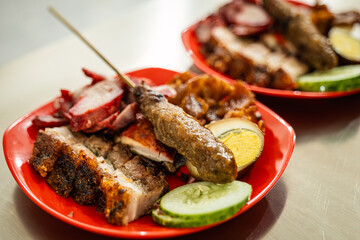 The menu at a Chinese restaurant consists of roast pork, pork char siu, sausage, pig ears, skin, eggs, and pork satay. With cucumber slices.