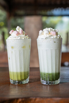Vanilla milk shake with avocado at the bottom of the glass. Topped with whipe cream and marsmallow.