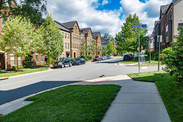 street in a residential neighborhood in the suburbs. Rows of apartment buildings with lawns along...