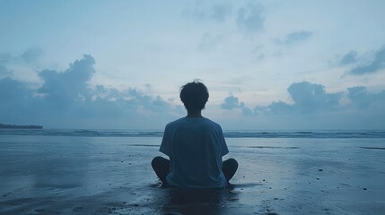 Fototapeta premium Person meditating on a beach at dawn.