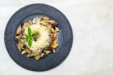 Pasta with black olives, Parmesan cheese, artichoke hearts, topped with fresh basil leaves.