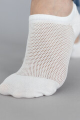 Close-up of a woman's legs in short white socks on a gray background