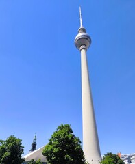 Obraz premium A low-angle view of the Fernsehturm (Television Tower) rising against a bright blue sky. Located in the heart of Berlin, Germany.