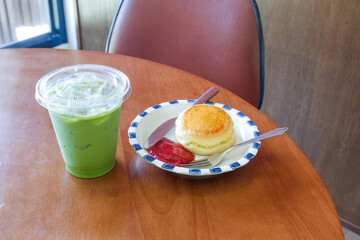 Healthy Matcha drink and Plate of Freshly baked scones served with butter and jam,Strawberry jam...