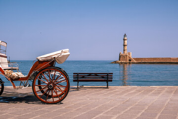 Chania Crete. Empty horse carriage and a bench with view to lighthouse, old venetian port