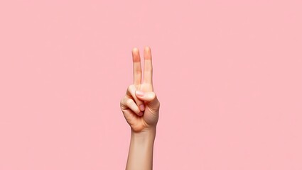 Hand gesture conveying peace or victory on a soft pink backdrop studio shot