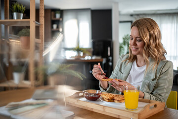 Businesswoman enjoying waffles and orange juice for breakfast at home