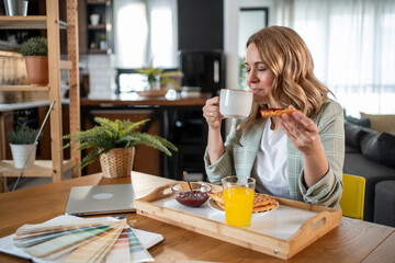 Interior designer enjoying breakfast and coffee while working at home