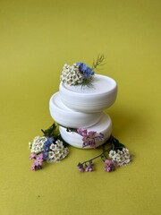 set of white jars with cream for skin care cosmetics on a light green background, advertising of...