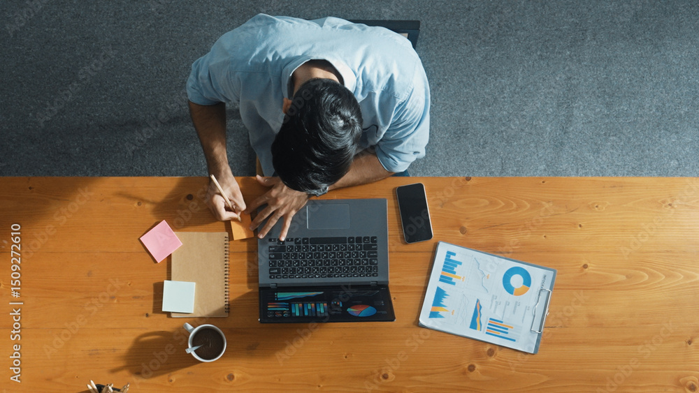 Poster skilled businessman writing idea on colorful sticky notes while looking at data analysis. caucasian 