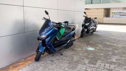 Blue and black scooters whisper urban journeys on cobblestones, echoing Vespa nostalgia, World...