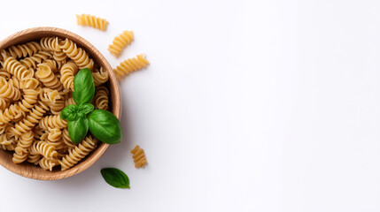 Uncooked fusilli pasta in wooden bowl with fresh basil leaves on white background Concept of healthy eating, vegetarian food, and Italian cuisine