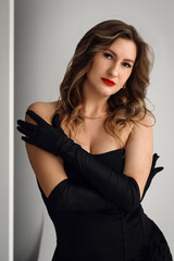 Portrait of beautiful young woman in black dress. long stylish gloves. girl luxury fashion model...