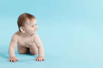 Cute little baby crawling on light blue background. Space for text