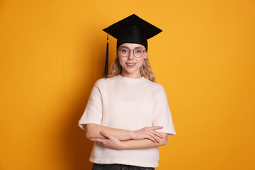 Happy student after graduation on orange background