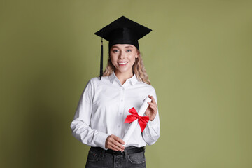 Happy student with diploma after graduation on green background