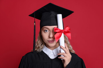 Beautiful student with diploma after graduation on red background