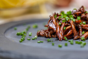 Shimeji mushroom served with chives on black stone plate. Typical oriental meal. Detail of food dish, closeup, selective focus.