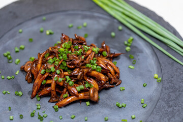 Shimeji mushroom served with chives on black stone plate. Typical oriental meal. Detail of food...