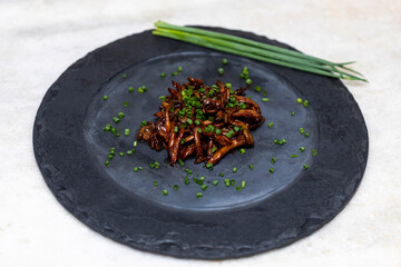 Shimeji mushroom served with chives on black stone plate. Typical oriental meal. Detail of food...