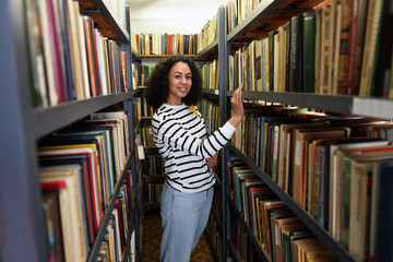 Woman with laptop near shelves in public library