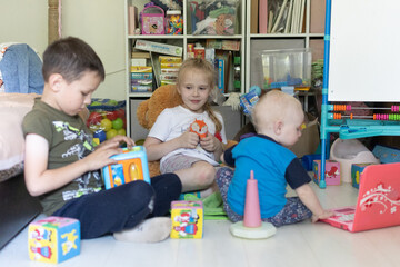 Three children are playing. Children's room with children.Two children playing with a toddler