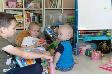Three children are playing. Children's room with children.Two children playing with a toddler