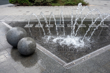 Outdoor decorative fountain with round marble sculptures and flowing water streams.