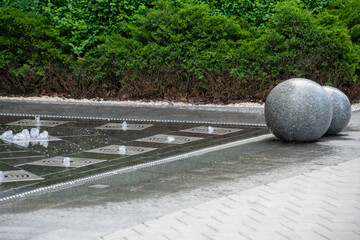 Outdoor decorative fountain with round marble sculptures and flowing water streams.