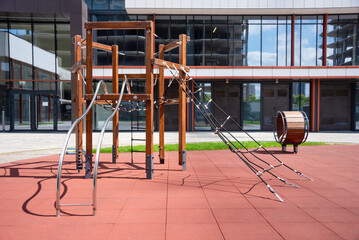 Outdoor playground structure featuring wooden and rope elements in a modern urban setting, activities for children in a safe environment. Enclosed by apartment buildings, perfect for families to enjoy