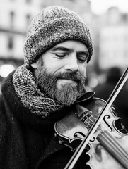Black and white photograph of a man playing the violin. he is wearing a knitted beanie and a scarf around his neck.