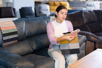 pensive girl imagines how sofa will look in selected upholstery or cover