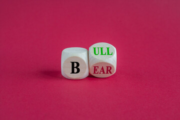 Symbol for a positive trend at the stock market. Turned a wooden cube and changes the word 'bear' to 'bull'. Beautiful red background. Business and bear or bull concept.