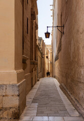 Obraz premium Narrow alleyway in the old city of Mdina with traditional lanterns, ragged limestone houses and tranquil atmosphere, Maltese Islands.