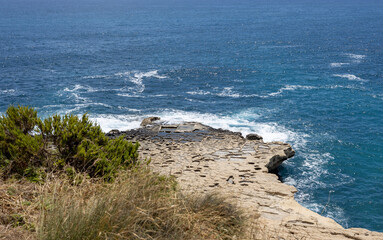 Beautiful Maltese coast with unique rock formations and arches, traditional salt panes and turquoise blue water near St Peter's Pool.