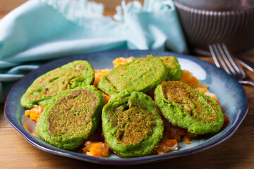 Green pea cakes on mashed carrot and parsnip. Vegetable fritters, pancakes on blue plate