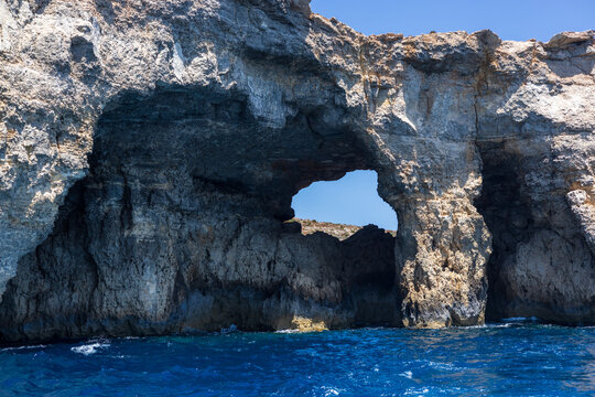 Rock formations of Caminotto Reef, Comino Island, Malta, against deep blue sea and clear sky.