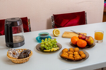 The dining table on it has fruits, juice, cakes, tea,