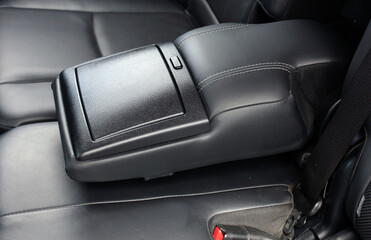 Close-up of rear passenger seat armrest. Black leather rear passenger seats in luxury car. Premium...