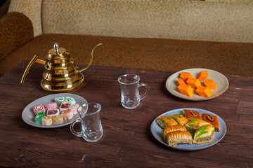 Oriental sweets baklava and lukum on a dark wooden table next to a Turkish teapot