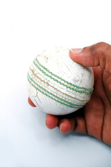 Cricket ball holding hand on white background close-up view 