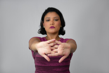 Beautiful and serious woman stretching her arms forward. Ideal for home workout, exercising, warm-up and physiotherapy. Neutral gray background with copy space. Focus on foreground.