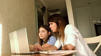 Happy mother with preteen daughter using laptop in home kitchen. Working on school project. Helping with homework using technologies - Powered by Adobe