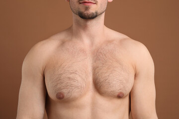 Young man with hairy chest on brown background, closeup. Epilation procedure